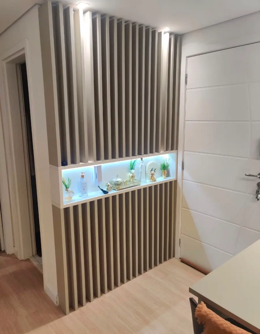 Painel ripado com nicho iluminado na entrada do apartamento